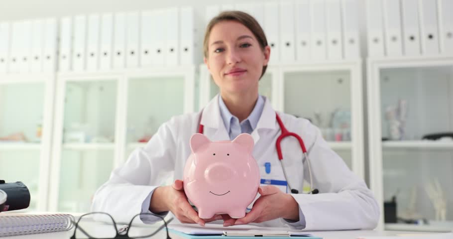 Doctor medical therapist holds piggy bank. Cost of healthcare saving money and health insurance Royalty-Free Stock Footage #1111506857