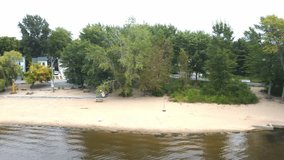 Aerial drone video filming the Laval-Ouest beach from overt he water, panning from left to right
