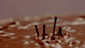 Slow motion video of waves of chocolate splashing and scattering in small drops.