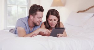 Couple, tablet and happy on bed, morning and laughing for funny meme, video or post on web blog in home. Man, woman and digital touchscreen with comic joke, scroll and click on social media in house
