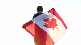 A young guy holds a Canadian flag in his hands at sunset. 4k video.