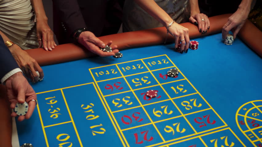 Anonymous Group of Rich Men and Women Gathered Around a Roulette Table at a Modern Casino. Cinematic Close Up Footage of Gambler Hands Placing Bets while the Ball Spinning in a Roulette Wheel Royalty-Free Stock Footage #1111518007