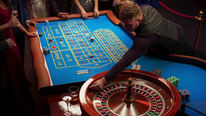 High Angle Footage of People Taking Risks and Placing Bets on a Roulette Wheel in a Casino. Croupier Placing a Ball into the Wheel, Focused on Table with Tokens, while Ball Spins on the Ball Track | Shutterstock HD Video #1111518009