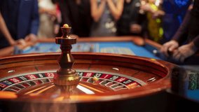 Anonymous Group of Elegant Casino Guests Placing Bets on a Table. Focus Switching to a Close Up Footage of a Spinning Roulette Wheel with a Ball Stopping at Number One Red - Powered by Shutterstock - Get 15% off with code: PIKWIZARD15