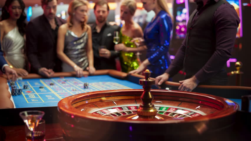 Gathering of Wealthy Young Individuals, Standing Together Around a Roulette Table in a Contemporary Casino Setting. Cinematic Nightlife Footage, Carefree Gamblers Congratulating the Winning Players Royalty-Free Stock Footage #1111518027
