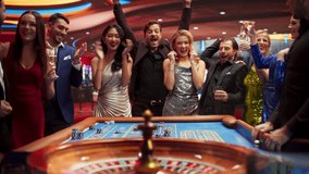 Gathering of Wealthy Young Individuals, Standing Together Around a Roulette Table in a Contemporary Casino Setting. Cinematic Nightlife Footage, Carefree Gamblers Congratulating the Winning Players - Powered by Shutterstock - Get 15% off with code: PIKWIZARD15
