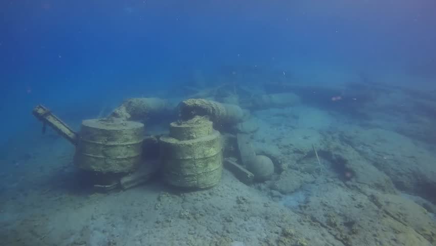 Reinforced concrete pier destroyed by strong storm, among the rubble lies an old stone cannonball on seabed, Underwater shot, Slow motion, Camera moving forwards. Mediterranean Sea, Greece