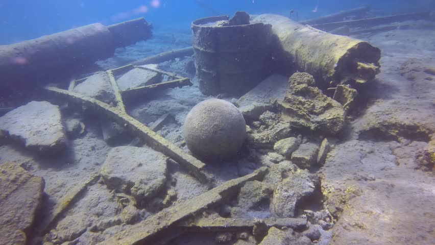 Reinforced concrete pier destroyed by strong storm, among the rubble lies an old stone cannonball on seabed, Underwater shot, Slow motion, Camera moving forwards. Mediterranean Sea, Greece