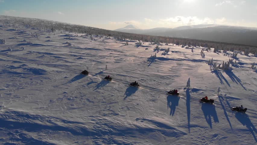 Extreme snowmobiling tours, group of snowmobile riders driving in the arctic region, aerial video. exciting winter sports and recreation, sunset winter landscape | Shutterstock HD Video #1111519159