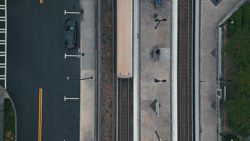 Aerial top down shot of train riding on rail in city of Atlanta with cars in road during cloudy day