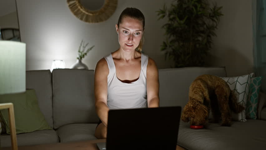 Young caucasian woman with dog smiling using laptop sitting on the sofa at home