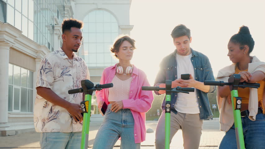 Multiracial friends communicate with each other before riding shared electric push scooters in the city. Rental electric transportation. | Shutterstock HD Video #1111524009