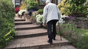 Elderly man walks up steps to his home a walking stick, England - Powered by Shutterstock - Get 15% off with code: PIKWIZARD15
