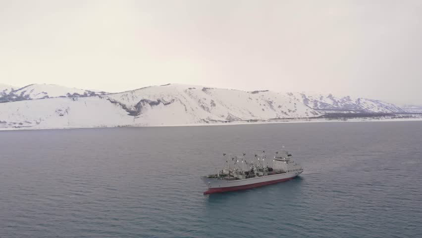 Two ships at sea by the snow-covered hills. 
