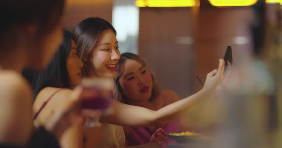 Beautiful young asian woman using phone and taking selfie with friend in bar. They Enjoying with Night Party Together. Party, Lifestyle, Happiness, Cheerful and Celebration Concept. | Shutterstock HD Video #1111527599