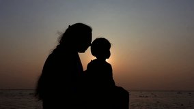 An Asian mother and her child are enjoying the evening river view at sunset time. Silhouette view of a mom and kid having fun. A child with parents on holiday conceptual 4k video.