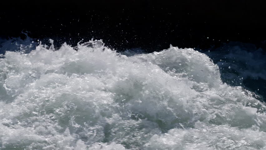 slow-motion shooting of water splashes in a fast mountain river close-up. bright light in the foreground, shadow in the background