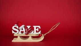 Christmas sale banner. The sled moves on a red background, the word sale appears, decorated with a Santa hat, a warm scarf and Christmas balls. Stop motion animation - Powered by Shutterstock - Get 15% off with code: PIKWIZARD15