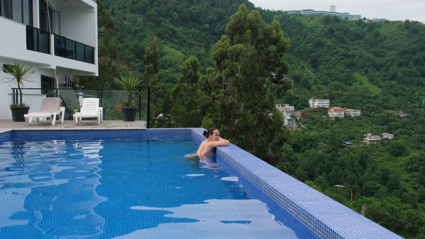 Young Caucasian woman enjoying amazing view while resting in infinity pool. Summer vacation concept  Royalty-Free Stock Footage #1111539601