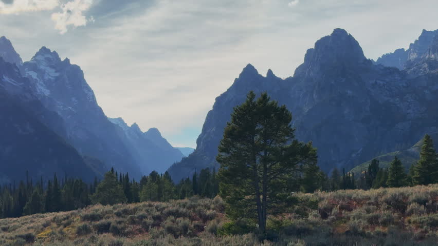 Jenny String Lake roadway scenic views Grand Tetons National Park Mount Moran peak sun beam stunning autumn fall perfect weather mid late day afternoon sunset clouds cinematic pan left slowly motion