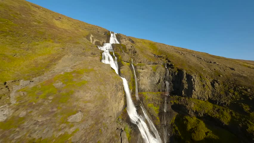 FPV aerial footage of the large Glymor waterfall, flying upwards stream in scenic landcape, Iceland.