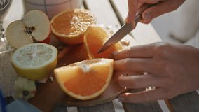 Closeup woman hands cutting orange on wooden board at summer balcony. Anonymous lady holding knife chopping fruits at sunshine terrace. Unrecognizable model preparing breakfast at open air place - Powered by Shutterstock - Get 15% off with code: PIKWIZARD15