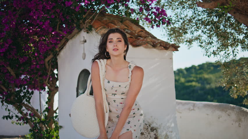 Portrait girl posing summer garden near church. Sensual calm woman standing up rock walking windy mountains cityscape closeup. Romantic gentle lady touching hair looking camera at greenery nature