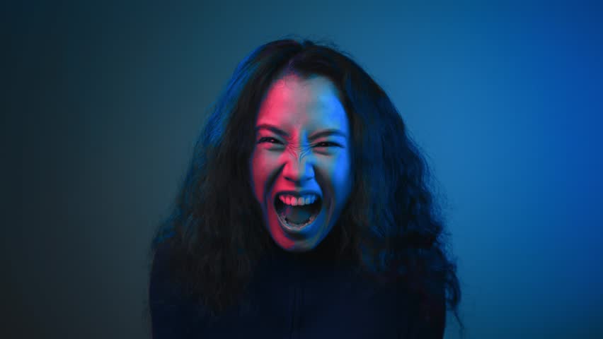 Portrait of Asian Woman Looking at Camera and Screaming in Neon Colors of Bright Studio. Headshot of Young 20s Girl Shouting in Crisis Madness. Suffering Face of Raging Person in Intense Brutal Hate | Shutterstock HD Video #1111552071