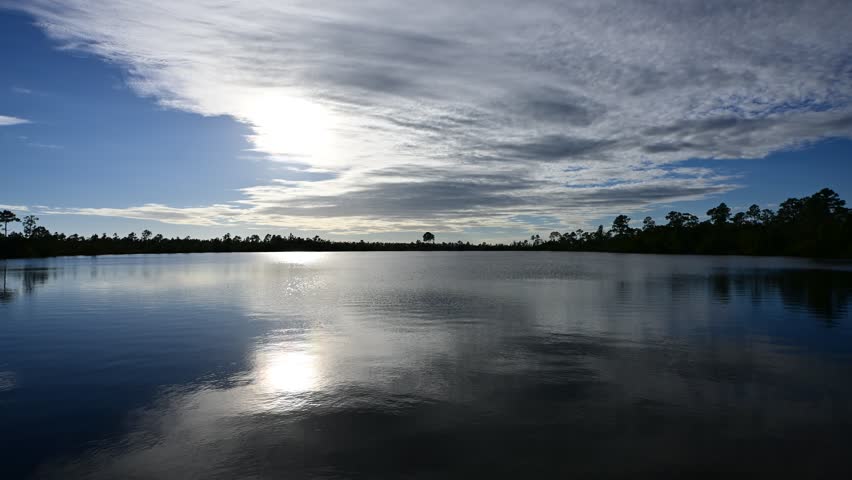 Time lapse of silver gray afternoon cloudscape developing then dissipating over Pine Glades Lake in Everglades National Park, Florida 4K..