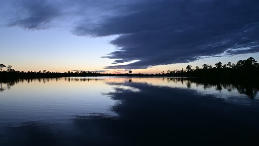 Timelapse of sunset cloudscape and twilight over Pine Glades Lake in Everglades National Park, Florida on calm autumn afternoon 4K.