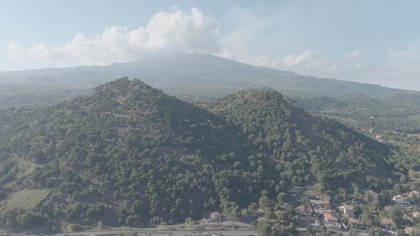 Nicolosi, Sicily, Italy. The Monti Rossi twin volcanic cones rise from the southern flank of Mount Etna, now blanketed by a dense pine forest that has reclaimed the 1669 eruption site. These two coalescent craters, formed during Etna