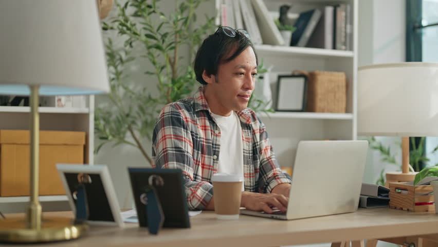 mature adult japanese male working at home man using laptop with cheerful ralax caual working in living room at home 