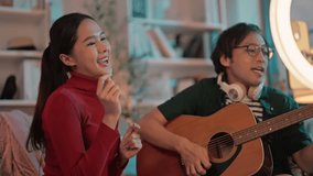 happiness Asian couple friends playing guitar music together through a lives stream performance broadcast on the smartphone internet. amateur music vlogger online Having fun show while staying at home