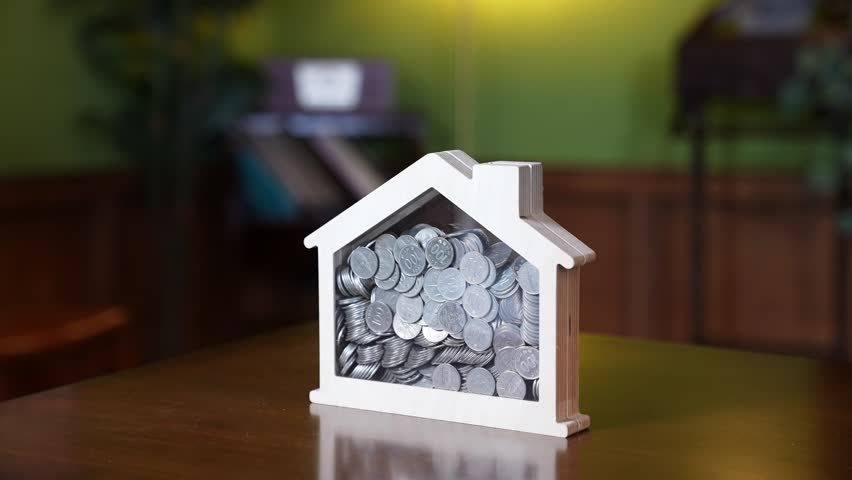 Coins in a house model's piggy bank Royalty-Free Stock Footage #1111559587