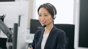 Asian operator wearing a headset to call a customer in a call center. - Powered by Shutterstock - Get 15% off with code: PIKWIZARD15