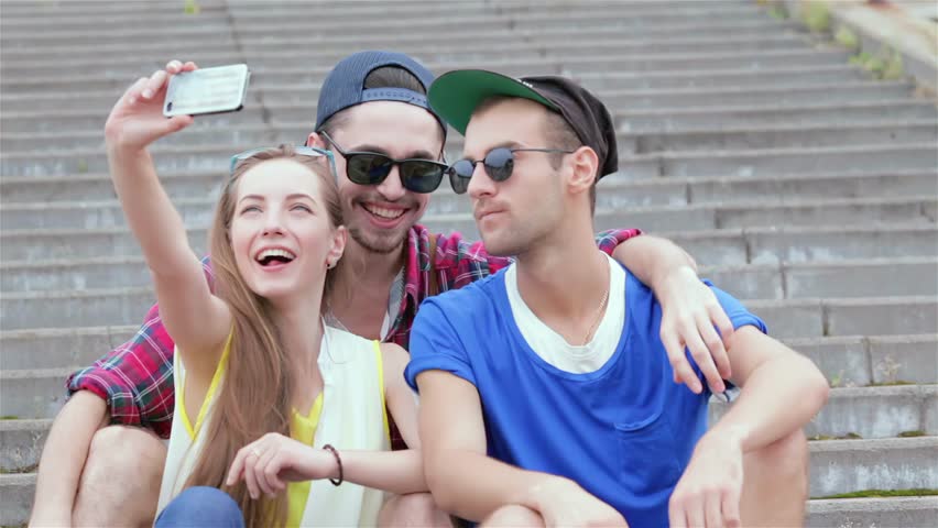 Cheerful girl sitting on the steps of his friends makes selfie | Shutterstock HD Video #1111565193