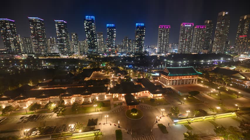 Time lapse of Skyscraper building illumination with car driving in traditional hotel at Songdo Central Park, Incheon, South Korea