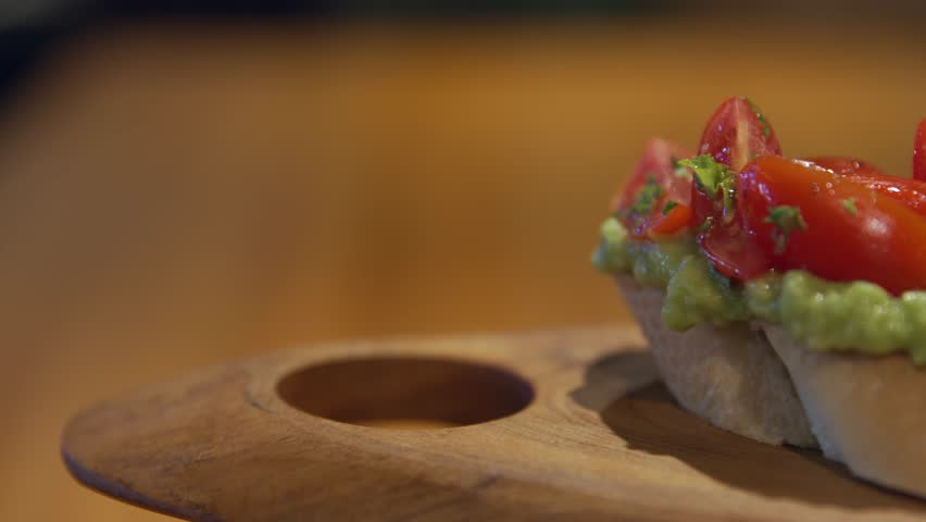 The camera pans over a perfect breakfast with bruschettas with avocado, cherry tomatoes, eggs and mushrooms. Sandwiches and avocado toast and breakfast with toppings. Avocado on bread.