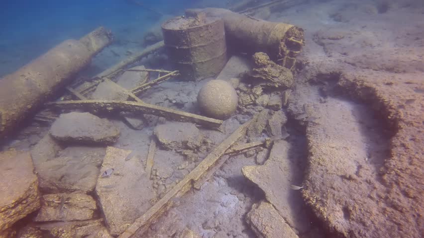 Reinforced concrete pier destroyed by strong storm, among the rubble lies an old stone cannonball on seabed, Underwater shot, Slow motion, Camera moving forwards. Mediterranean Sea, Greece
