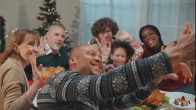 Multi-ethnic family using mobile phone video call online to relative. Attractive diverse group of people having dinner eating food to celebrate holiday Thanksgiving, X-mas eve on dining table at home. - Powered by Shutterstock - Get 15% off with code: PIKWIZARD15