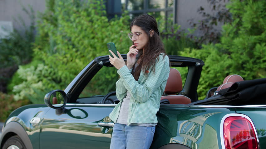 Woman Reading Bad News standing near Car. Female driver frustrated browsing cellphone. Bad news on her Smartphone. | Shutterstock HD Video #1111571917