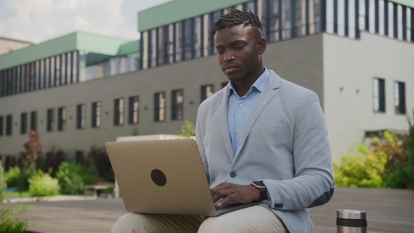 Black Businessman Suffering from Headache Outside. Overworked man has migraine working online using laptop. | Shutterstock HD Video #1111571953