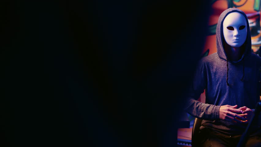 Dangerous hacker filming video threatening to launch cyber attack on another country government server if his demands are not met. Cybercriminal using smartphone to record blackmail message