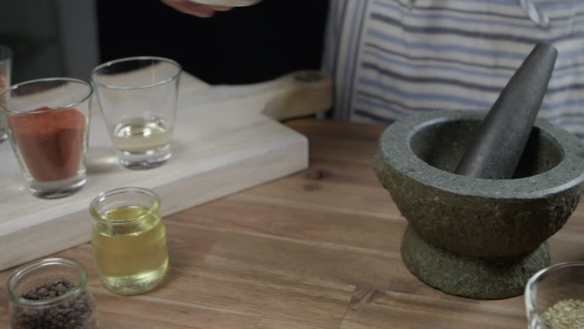 Homecook crush coarse salt in a mortar. Panning shot, no face.