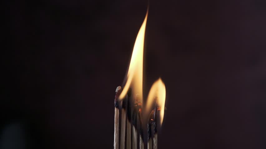 a row of matches are lit on a dark background