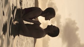 Romantic couple hugging and kissing in ocean at sunset - vertical video, jamesby island, tobago cays, st. vincent and the grenadines