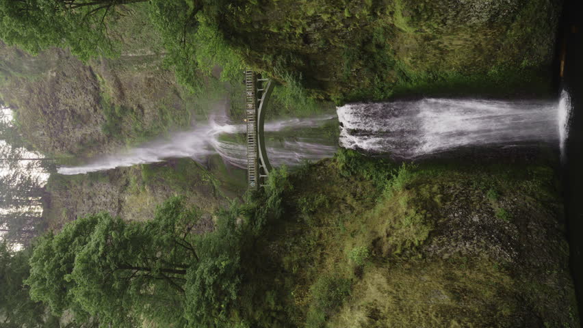 Panning shot of distant multnomah falls waterfall in green forest - vertical video, bridal veil, oregon, united states