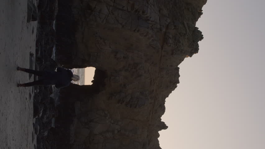 Woman photographing keyhole arch at sunset - vertical video, big sur, california, united states