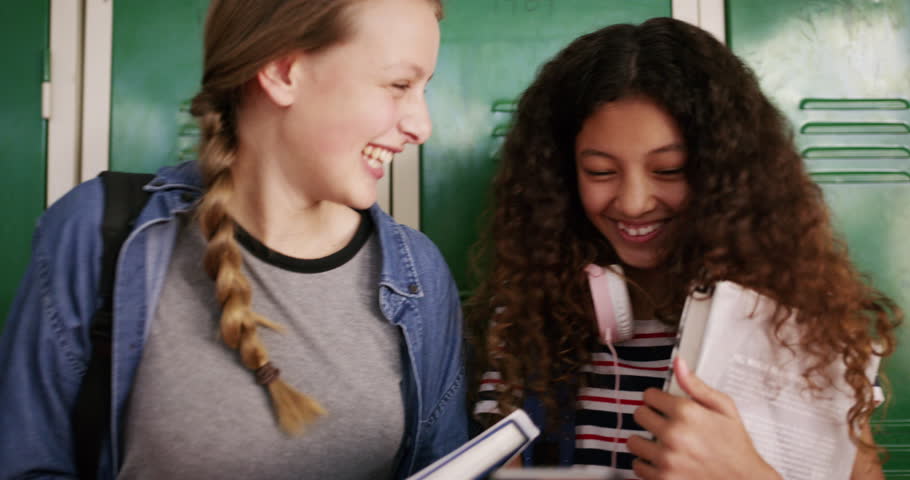 Locker, laugh and friends in school for learning, studying and knowledge in hallway. Education, teenager and happy young female students with textbooks, talking and speaking in academy corridor