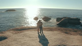 Couple, back and beach with sunset, pointing and horizon in summer on vacation, honeymoon and outdoor. Man, woman and hug with love, bonding or direction on rock, ocean or waves in sunshine in Brazil - Powered by Shutterstock - Get 15% off with code: PIKWIZARD15